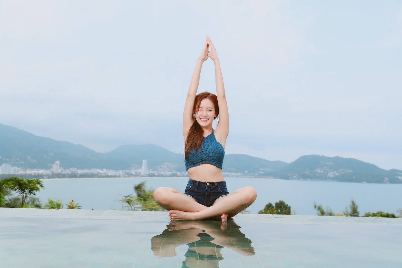 hero-img-02 Young woman doing yoga by a scenic waterfront, enjoying a serene landscape.